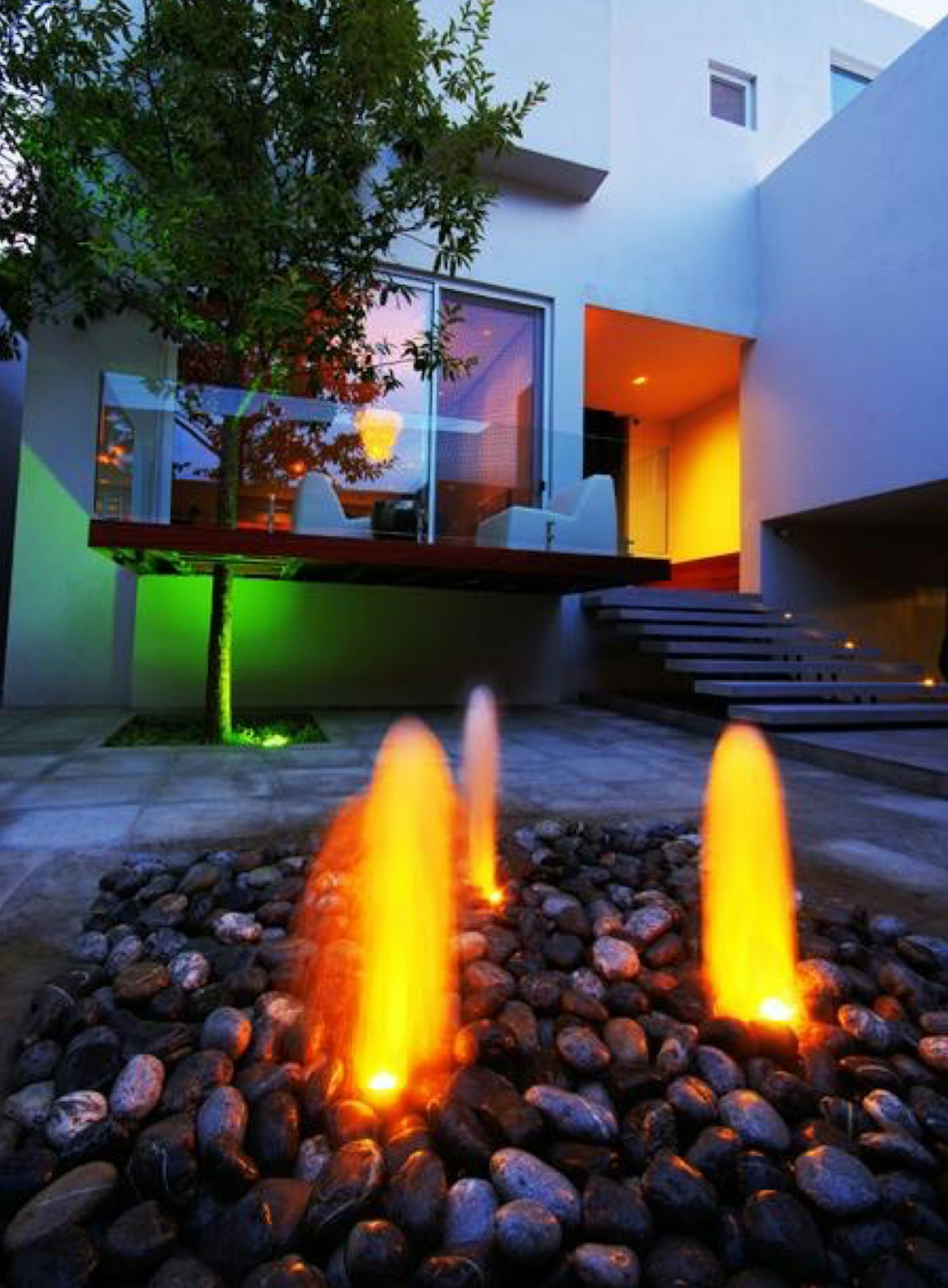 Entrada de casa con una fuente y luces ambientales